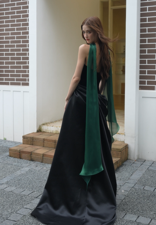 Elegant black strapless evening gown with open back, draped satin skirt and long emerald green scarf, back view