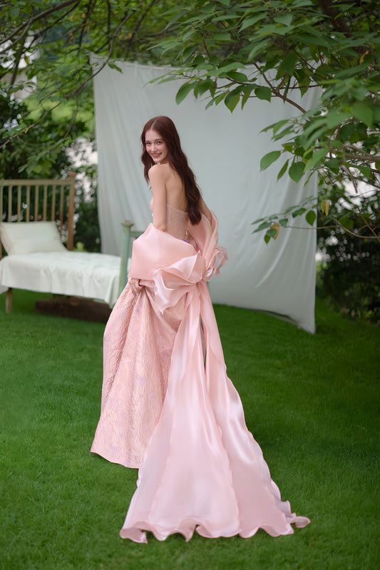 Romantic blush pink wedding dress with open back, oversized bow detail and long flowing train