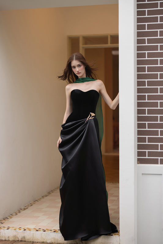 Black strapless evening gown with sweetheart neckline, asymmetric draped satin skirt and gold floral accent
