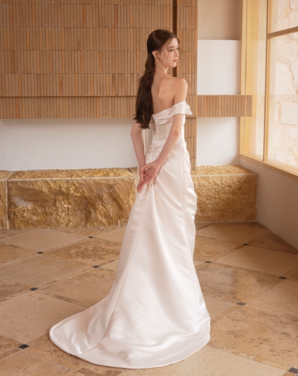 Back view of minimalist satin sheath wedding dress with off-the-shoulder neckline and train