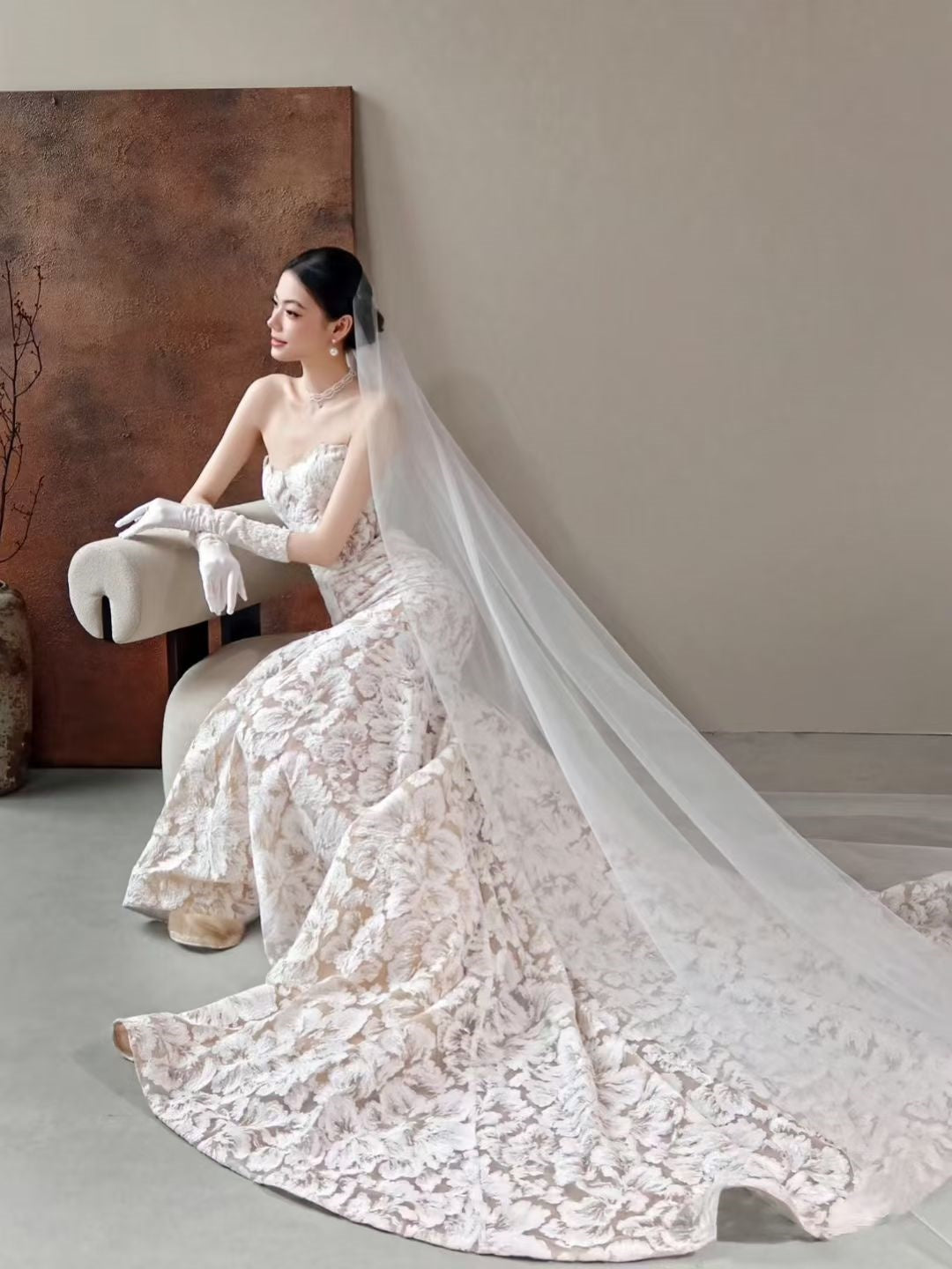 Luxury floral jacquard mermaid wedding dress with strapless neckline, textured floral fabric, long train, and sheer bridal veil