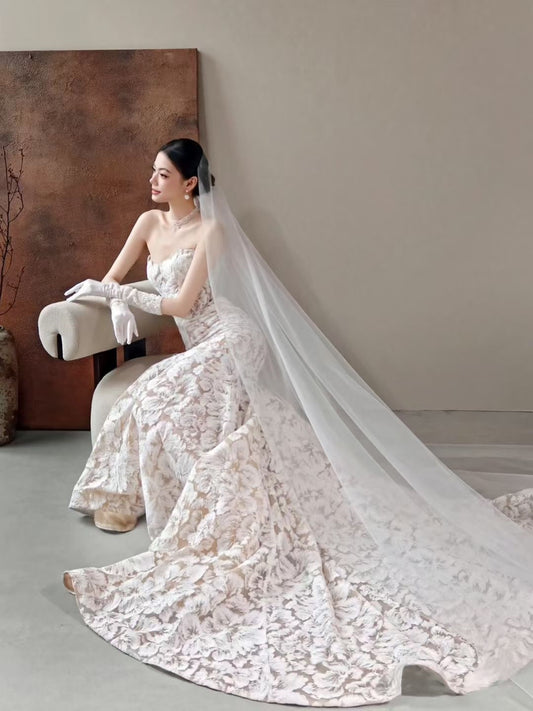 Luxury floral jacquard mermaid wedding dress with strapless neckline, textured floral fabric, long train, and sheer bridal veil