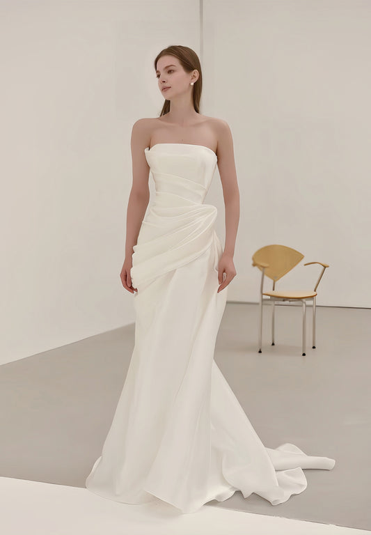 Minimalist draped satin strapless mermaid wedding dress with sculptural waist and sweep train