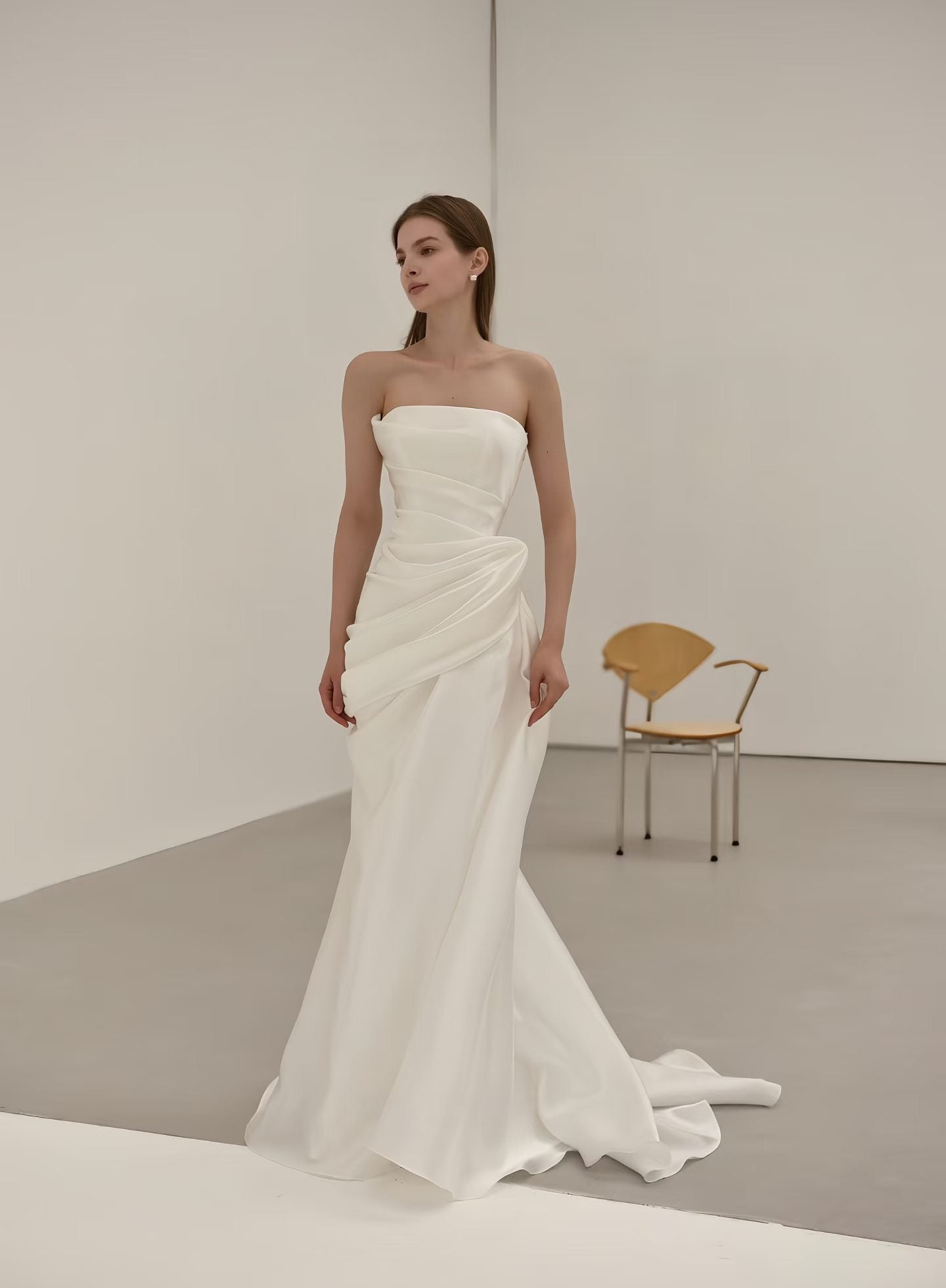 Minimalist draped satin strapless mermaid wedding dress with sculptural waist and sweep train