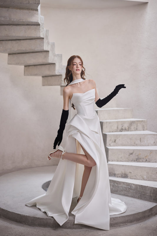 Modern strapless A-line wedding dress with structured bodice, asymmetric draping, high slit and bridal scarf