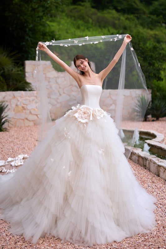 Romantic strapless 3D floral wedding dress with structured bodice and voluminous layered tulle ball gown skirt